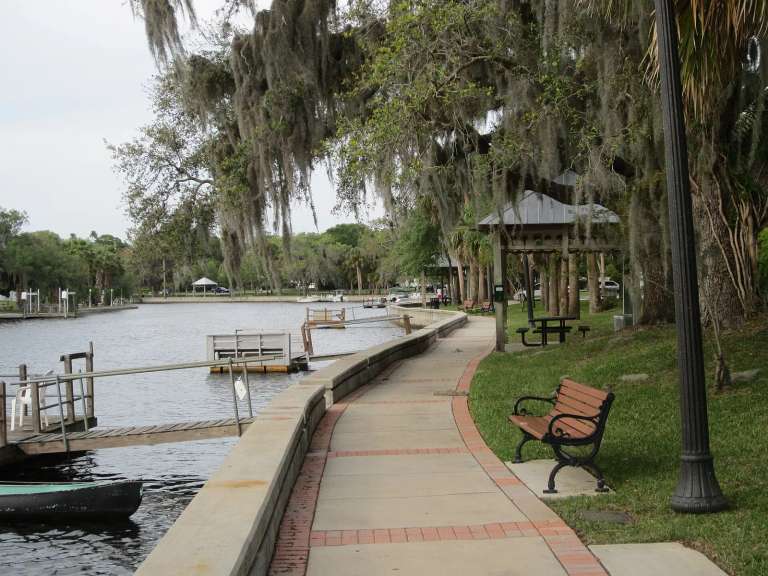 The riverwalk of Cotee River Park in New Port Richey: a brick-edged path, benches and a gazebo beside the water