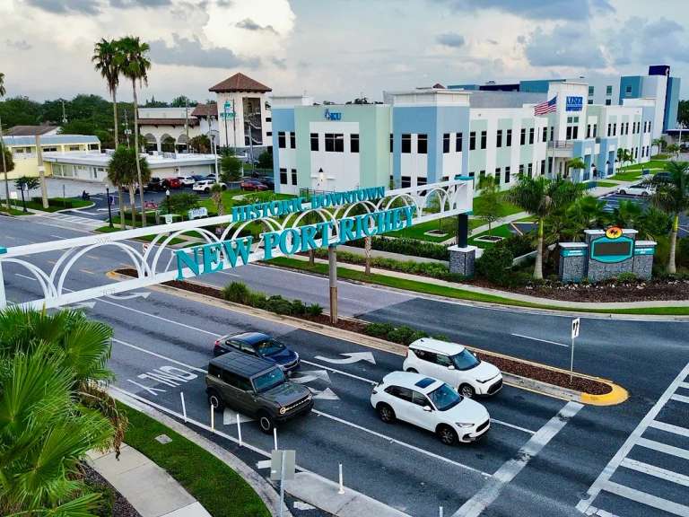 Vista aérea del arco de Historic Downtown New Port Richey sobre Main Street, con palmeras y las manzanas del centro detrás