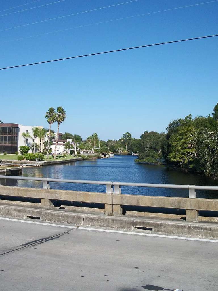 El río Pithlachascotee visto desde el puente de Grand Boulevard, con un edificio de condominios de tres plantas en la orilla izquierda