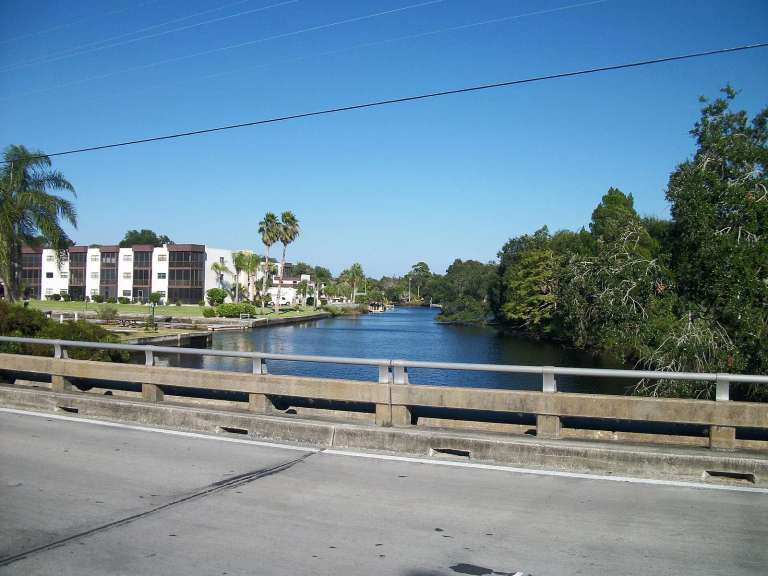 El río Pithlachascotee visto desde el puente de Grand Boulevard, con un edificio de condominios de tres plantas en la orilla izquierda
