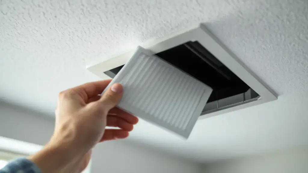 A close-up of a homeowner in a bright New Port Richey home sliding a fresh, clean pleated air filter into a ceiling-moun